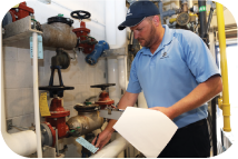 Photo: A man in a blue polo performing an inspection of a backflow preventer.