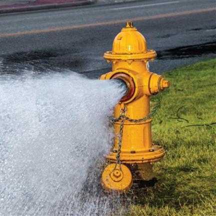 A yellow fire hydrant open with water rushing out